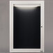 A white rectangular door with a black letter board inside and a light.