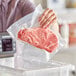 A woman's hand vacuum sealing a piece of meat in a VacPak-It pouch.