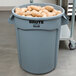 A Rubbermaid gray round trash can with a lid filled with potatoes.