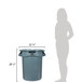 A woman standing next to a large grey Rubbermaid trash can with a black lid.