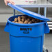 A blue Rubbermaid BRUTE trash can with potatoes inside.