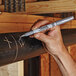 A hand using a Sharpie metallic silver marker to write on a pipe.
