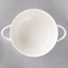 A close-up of a white Villeroy & Boch porcelain soup bowl with two handles.