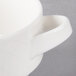 A close-up of a white porcelain soup cup with a handle.