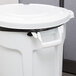 A white Rubbermaid BRUTE round trash can with black handles and lid.
