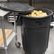 A Rubbermaid BRUTE 44 gallon black trash can filled with potatoes.