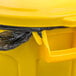 A yellow Rubbermaid BRUTE trash can with a black plastic bag inside.