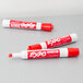 Three red Expo dry erase markers with white caps and tips.