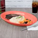 A Tuxton Cinnebar oval china platter with rice, vegetables, and meat on it.