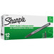 A box of 12 Sharpie black plastic point stick pens with black and gray barrels.