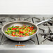 A Vollrath Wear-Ever non-stick fry pan with vegetables cooking on a stove.