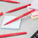A close-up of a Paper Mate red pen on a white notepad.