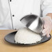 A person using a Matfer Bourgeat hemisphere mold to plate rice.
