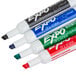 A group of Expo dry erase markers with white caps, in blue, green, red, and black.