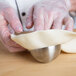 A person in gloves using a Matfer Bourgeat stainless steel hemisphere mold to shape dough.