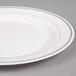 A WNA Comet white plastic plate with silver accent bands.
