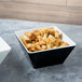 A white Vollrath melamine bowl filled with croutons on a table.