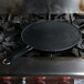 A Mastrad silicone splatter screen covering a pan on a stove.