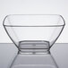 A clear small square Vollrath acrylic bowl on a reflective surface.