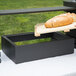 A loaf of bread on a wooden tray with a black wooden base.