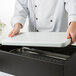 A chef using a Vollrath black wooden display base on a white counter.