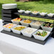 A Vollrath wood display template on a table with bowls of food.