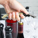 A hand using a Pulltap's Original olive corkscrew to open a wine bottle.