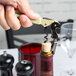 A hand using a Pulltap's Original Waiter's Corkscrew with an olive handle to open a bottle of wine.