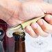 A hand opening a bottle with a Pulltap's Original waiter's corkscrew with an olive handle.