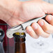 A hand using a Pulltap's Original Waiter's Corkscrew with a white handle to open a bottle.