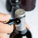 A hand using a Pulltap's Original Waiter's Corkscrew with an electric blue handle to open a bottle of wine.