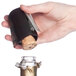 A hand using a Franmara champagne opener to remove a cork from a bottle of wine.