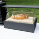A Vollrath acrylic roll top cover on a wood tray with a loaf of bread inside.