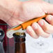 A person using a Pulltap's Original Waiter's Corkscrew with an orange handle to open a bottle.