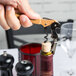A hand opening a bottle of wine with a Pulltap's Original Hazelnut Corkscrew.