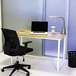 A Safco beech and white steel workstation with a laptop on the desk and a black office chair.