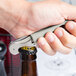 A hand holding a Pulltap's Original waiter's corkscrew with a silver gray handle opening a bottle.