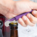 A hand using a Pulltap's purple waiter's corkscrew to open a bottle of wine.