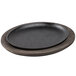 A Lodge oval black cast iron fajita pan on a walnut wood underliner.