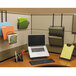 A black Safco Onyx desktop organizer with folders and papers in the compartments on a desk with a laptop.