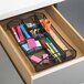 A black mesh drawer organizer with stationery in it.