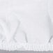 A white L.A. Baby crib pad cover with ruffles and a seam.