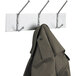 A Safco satin metal coat rack with three pegs holding a coat.
