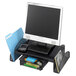 A Safco black mesh steel monitor stand with file folders and a cell phone on the counter.
