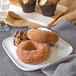 A white melamine square coupe plate with two chocolate covered donuts.