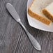 A plate with a slice of bread and a Oneida Scroll stainless steel butter knife.