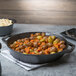 A Lodge cast iron skillet filled with potatoes and carrots on a table.