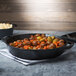 A Lodge cast iron skillet with potatoes and carrots on a table.