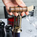 A person using a Franmara vintage style corkscrew with a brush to open a wine bottle.