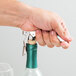 A hand uses a Franmara Duo-Lever corkscrew with a white enamel handle to open a bottle of wine.